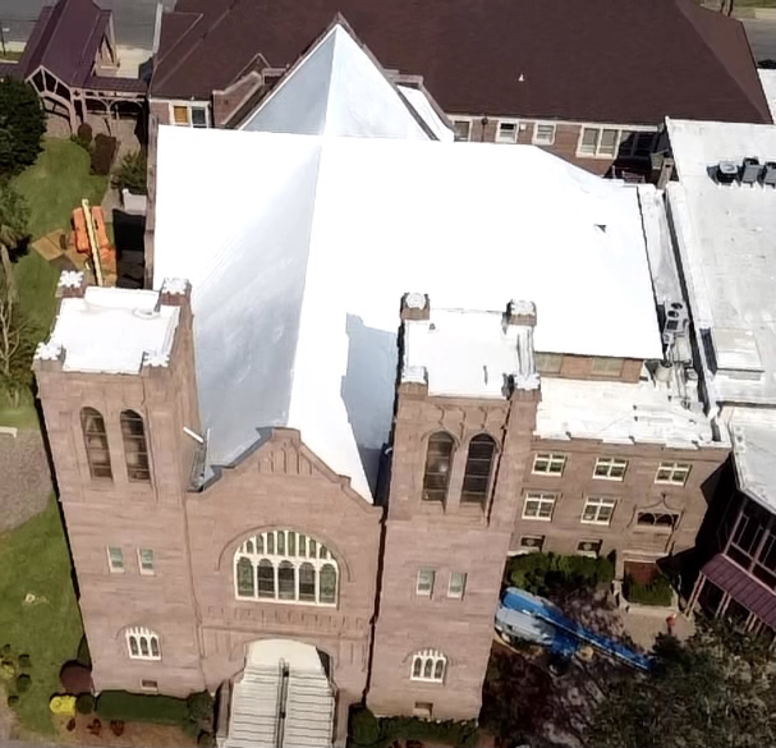 Historic brick church and tower under white shrink wrap roof protection