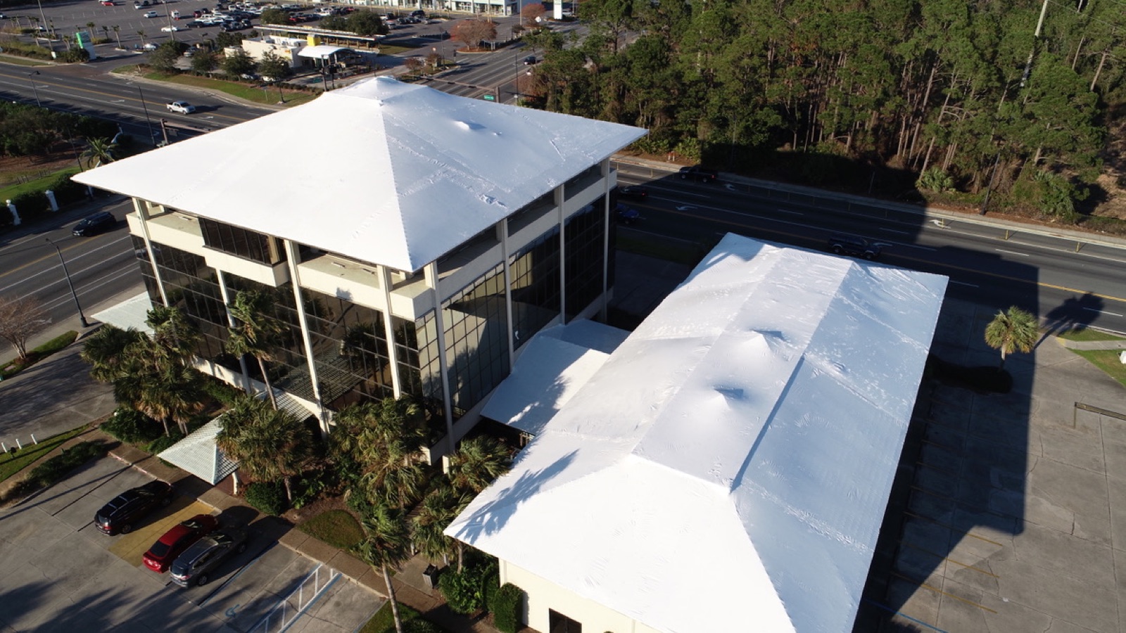 The same commercial buildings sealed under continuous white shrink wrap membranes