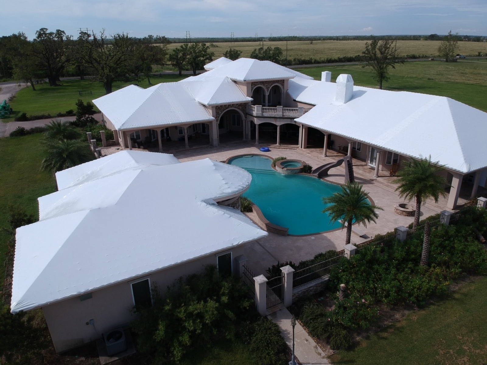 Emergency roof tarping on a large estate home after hurricane damage