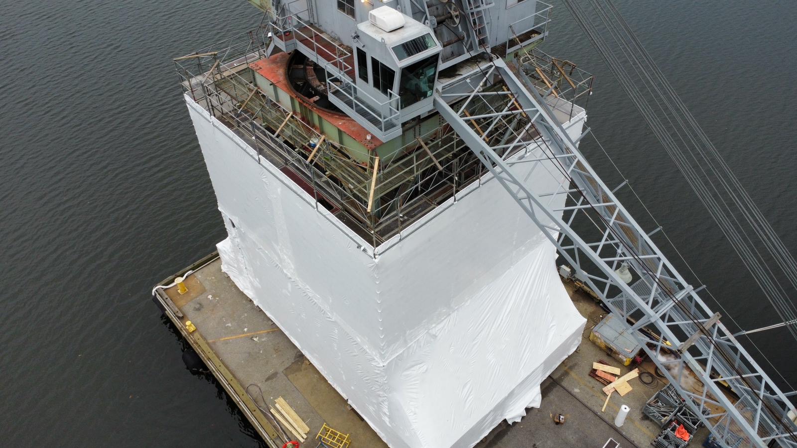 The government structure mid-installation, wrapped in white Elastowrap on the scaffolding