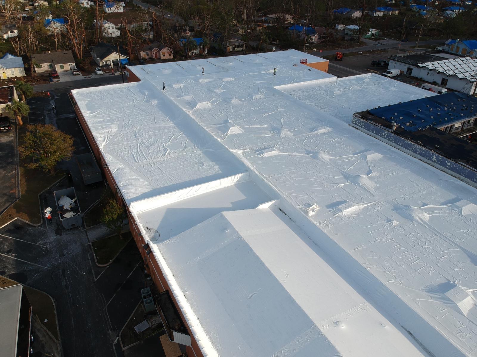 A large commercial roof sealed drum-tight under a white Titanium Tarps Elastowrap membrane