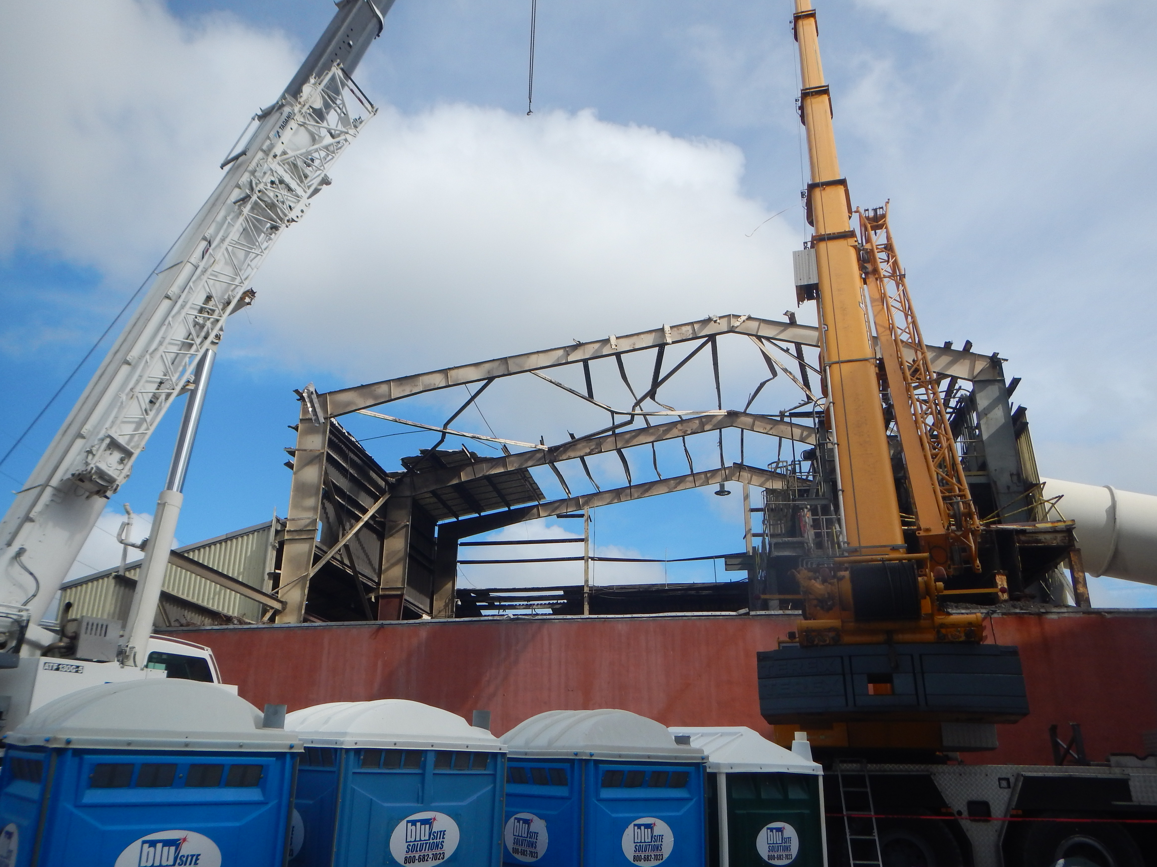 Industrial recycling plant with its roof structure torn open, crane on site