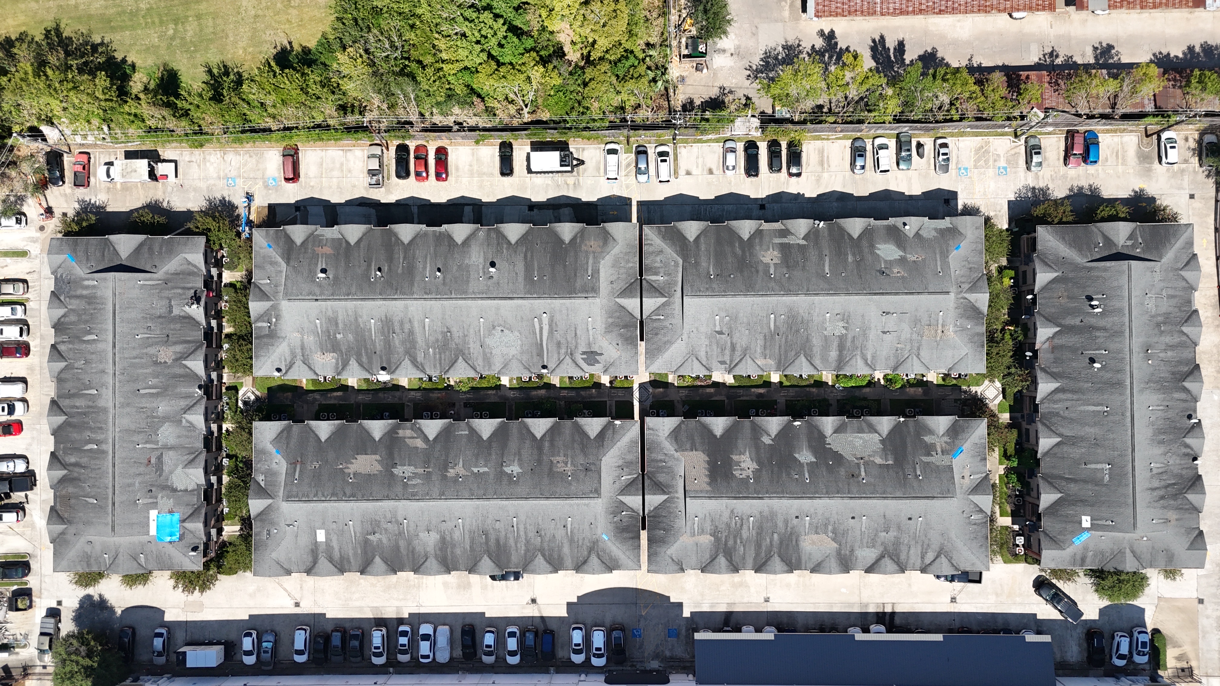 Six building apartment complex with dark aging roofs before Titanium Tarps