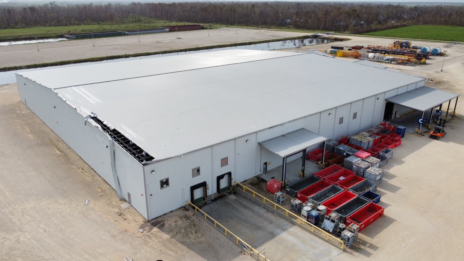 Houma shell warehouse with a storm-damaged roof before Titanium Tarps