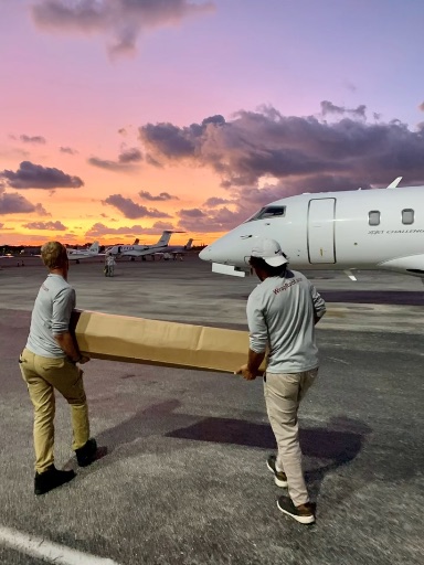 Titanium Tarps crew loading materials onto a chartered jet at sunset to reach a storm zone